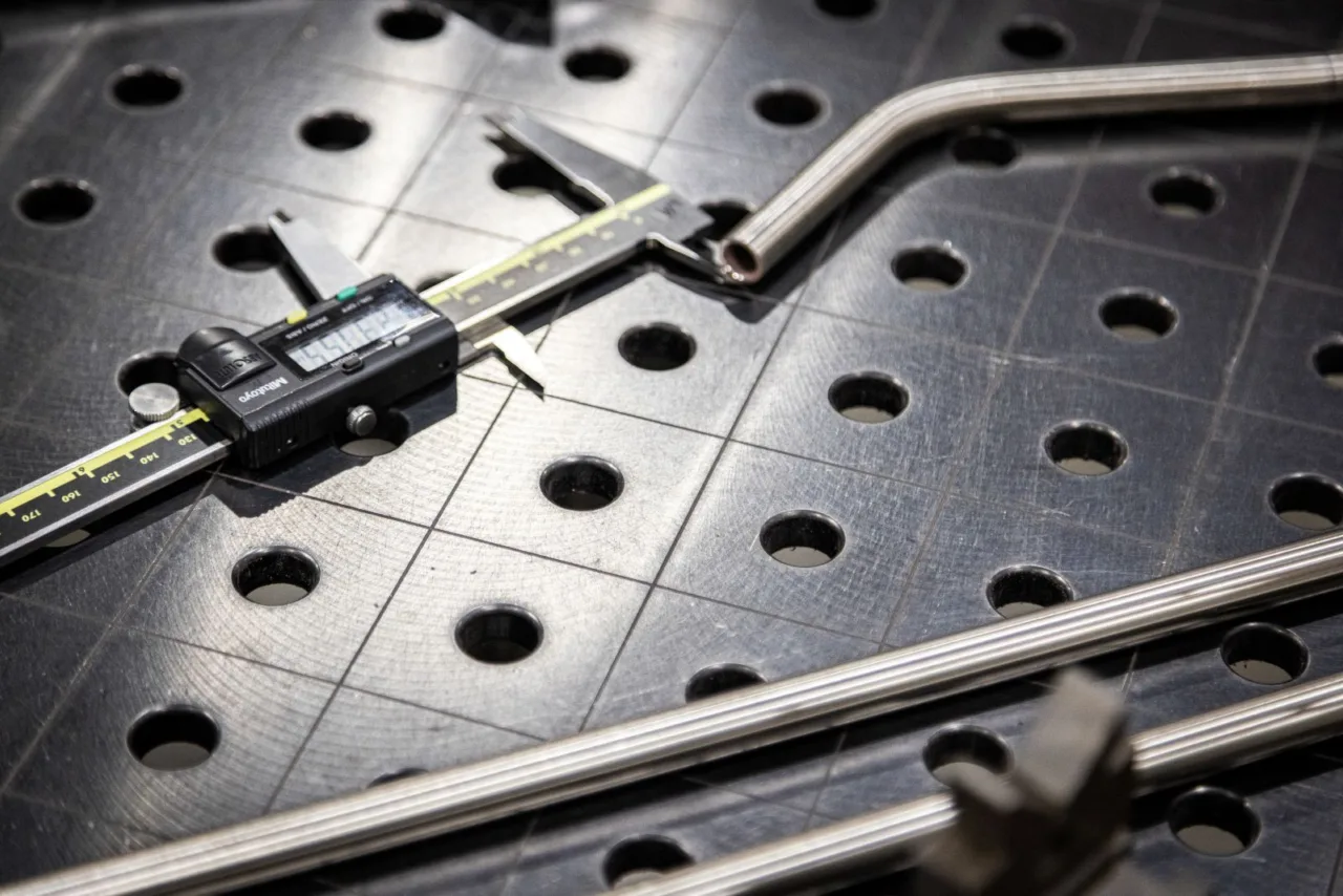 metal calipers and metal tubing sit on breadboard in industrial setting