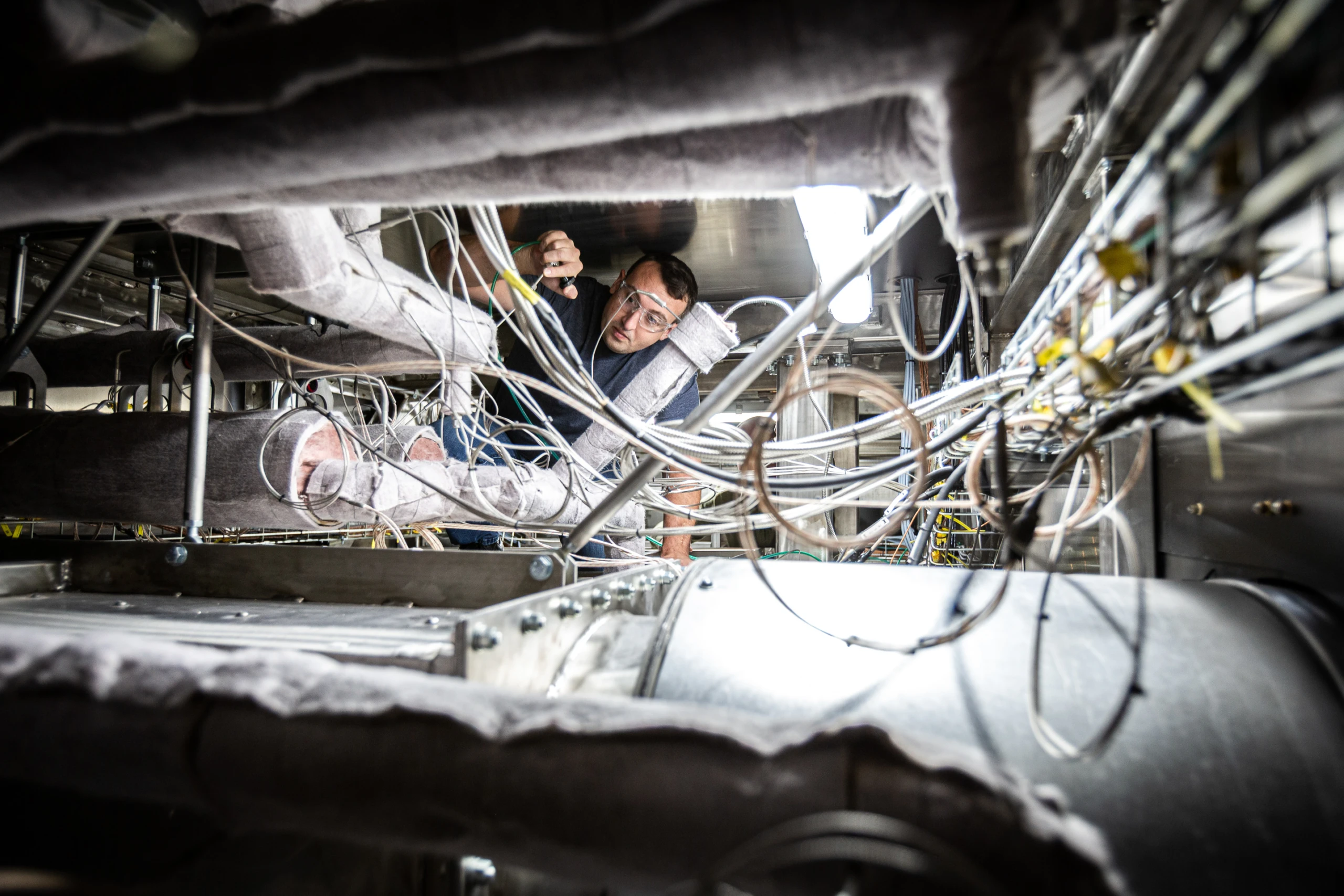 engineer wearing safety glasses adjusts tubing in Liquid Metal system