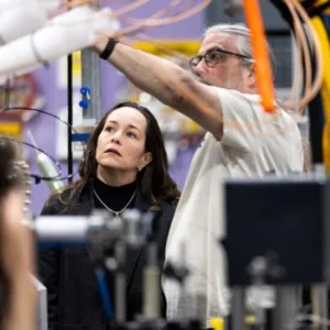 two scientists look at fusion device in industrial setting