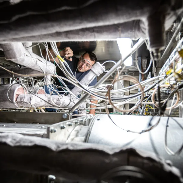 engineer wearing safety glasses adjusts tubing in Liquid Metal system