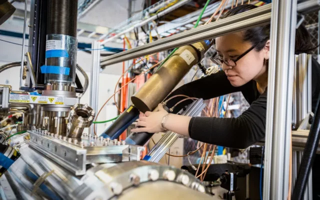 A scientist to the right of a Zap Energy fusion device adjusts measuring devices known as scintillators that measure neutrons.