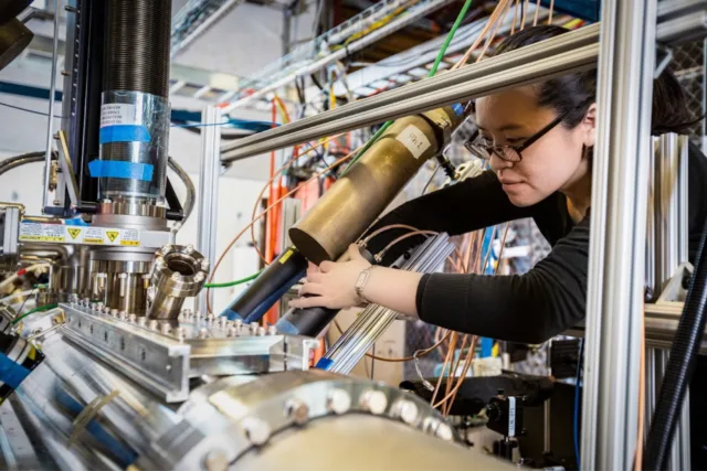 A scientist to the right of a Zap Energy fusion device adjusts measuring devices known as scintillators that measure neutrons.