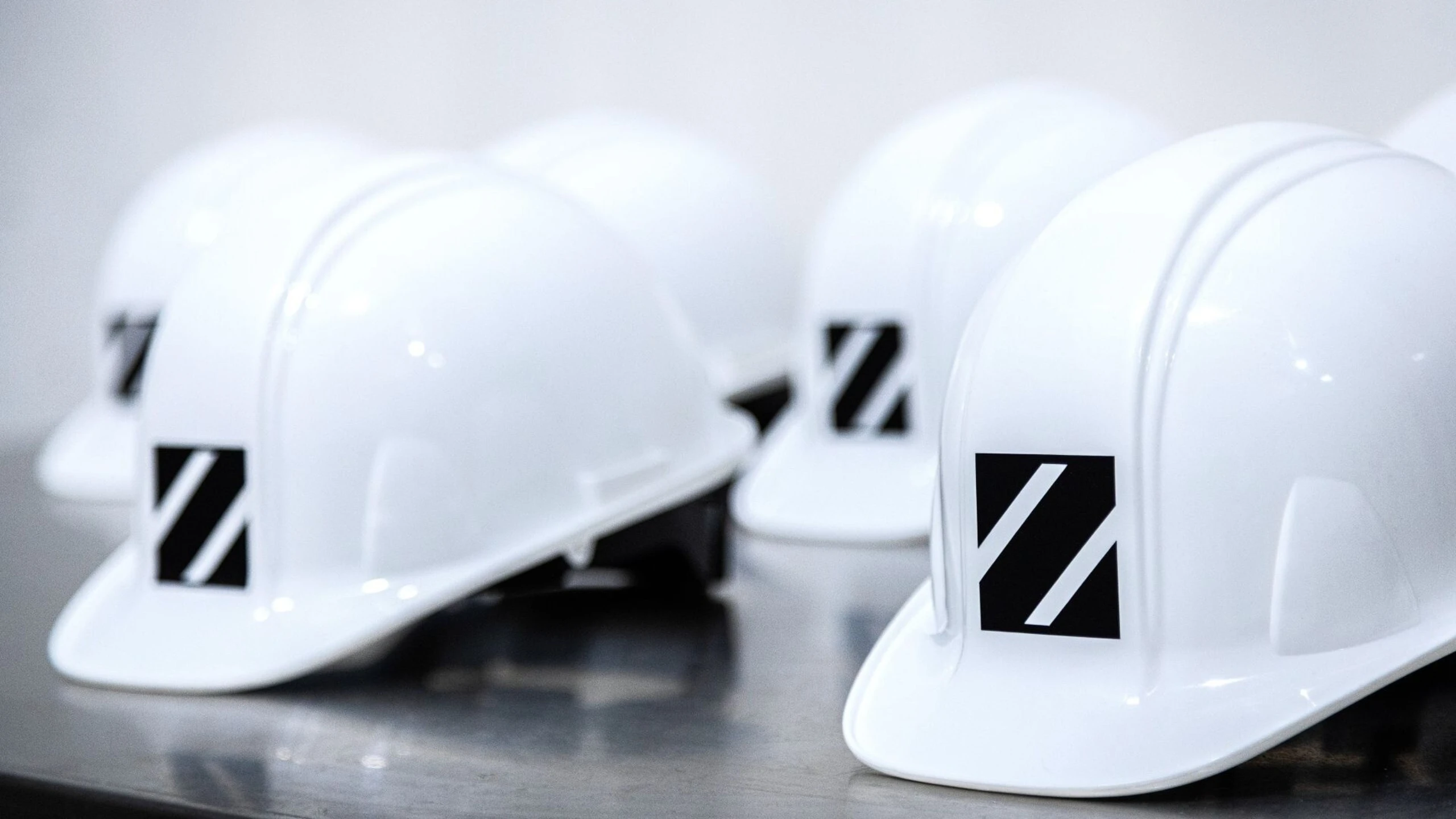 rows of white hard hats each with black Z logo on the front